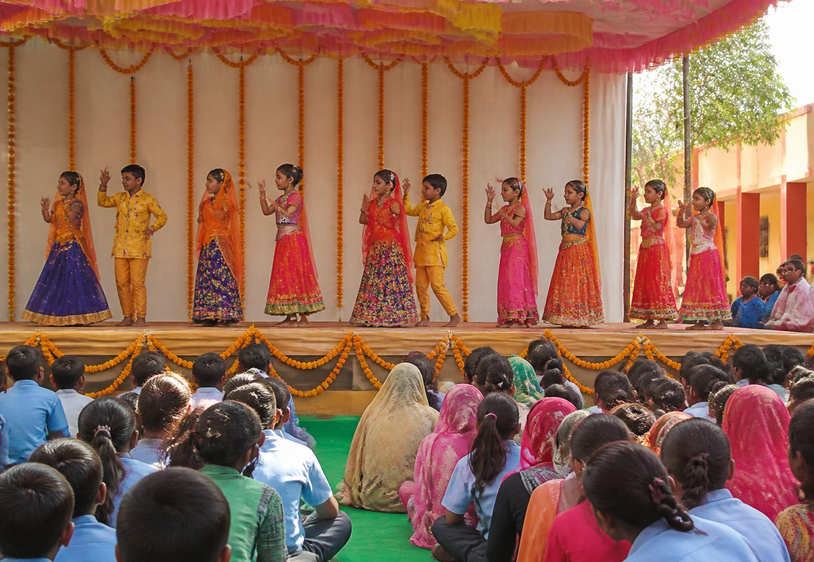 Students performing a cultural dance on stage during a school celebration